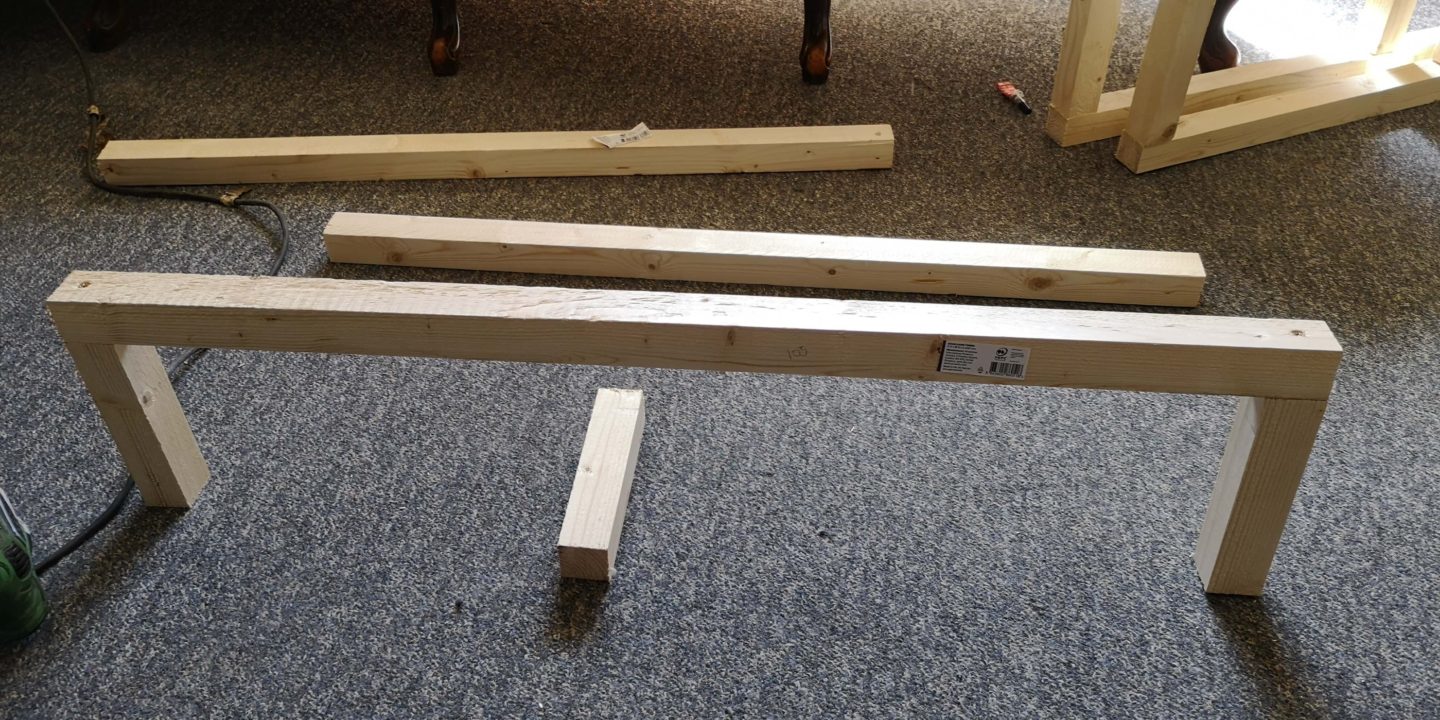 Two small spieces of timber standing up with a longer pieces laying on top of them. Ready to screw together.