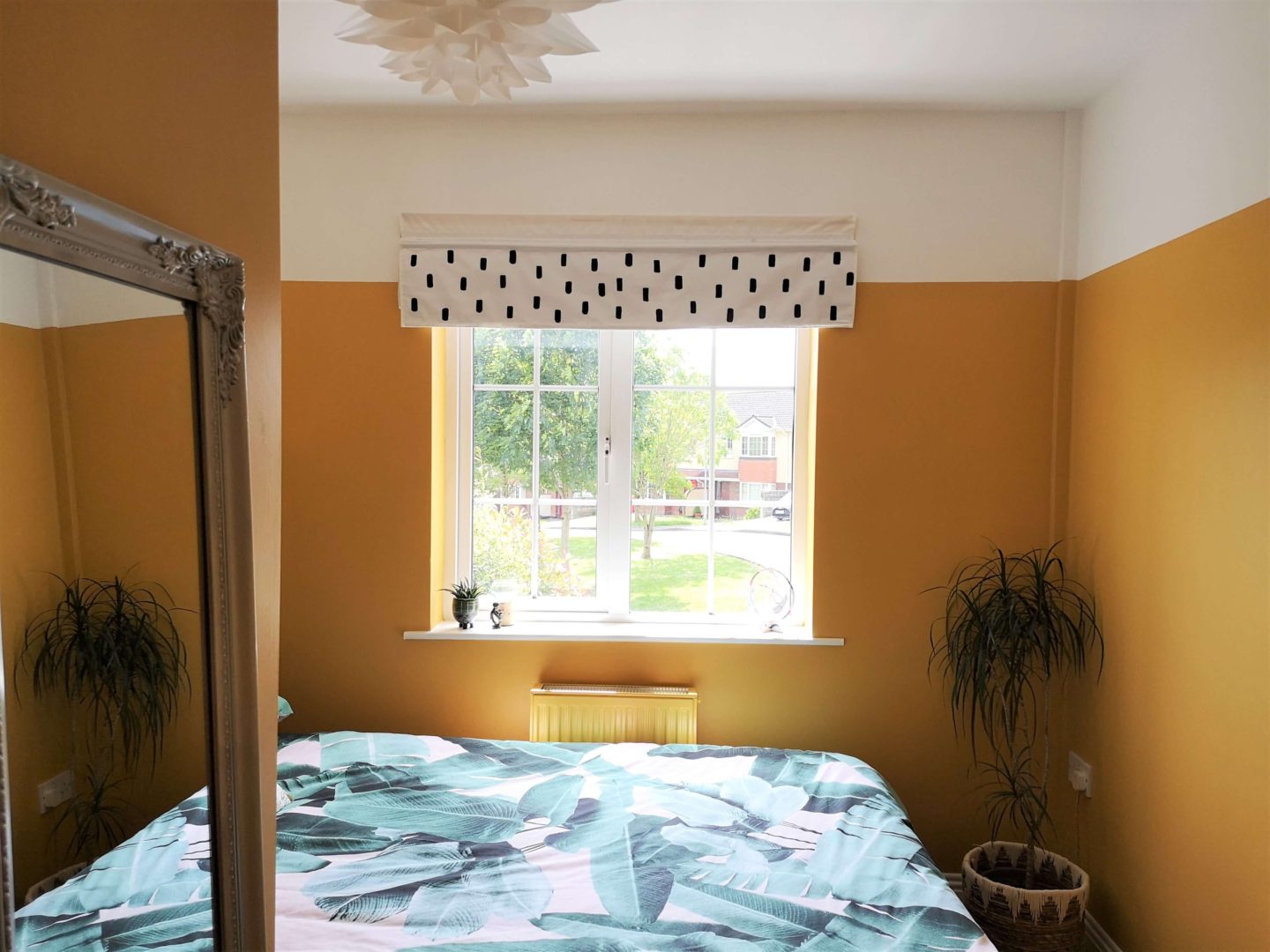 Mustard walls. White and black blind. Palm tree bedcovers. Silver full length mirror. 