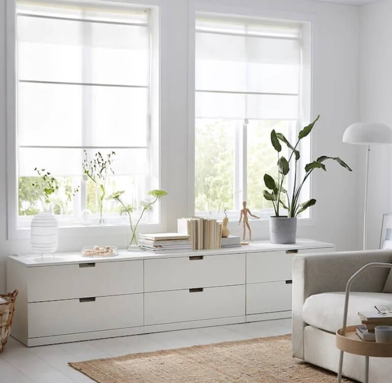 Two windows with white roman Ikea Ringblomma blind in a pale neutral living room.