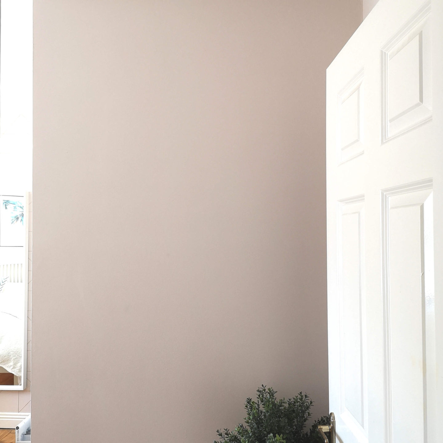 Blank pale pink wall just inside a bedroom door.
