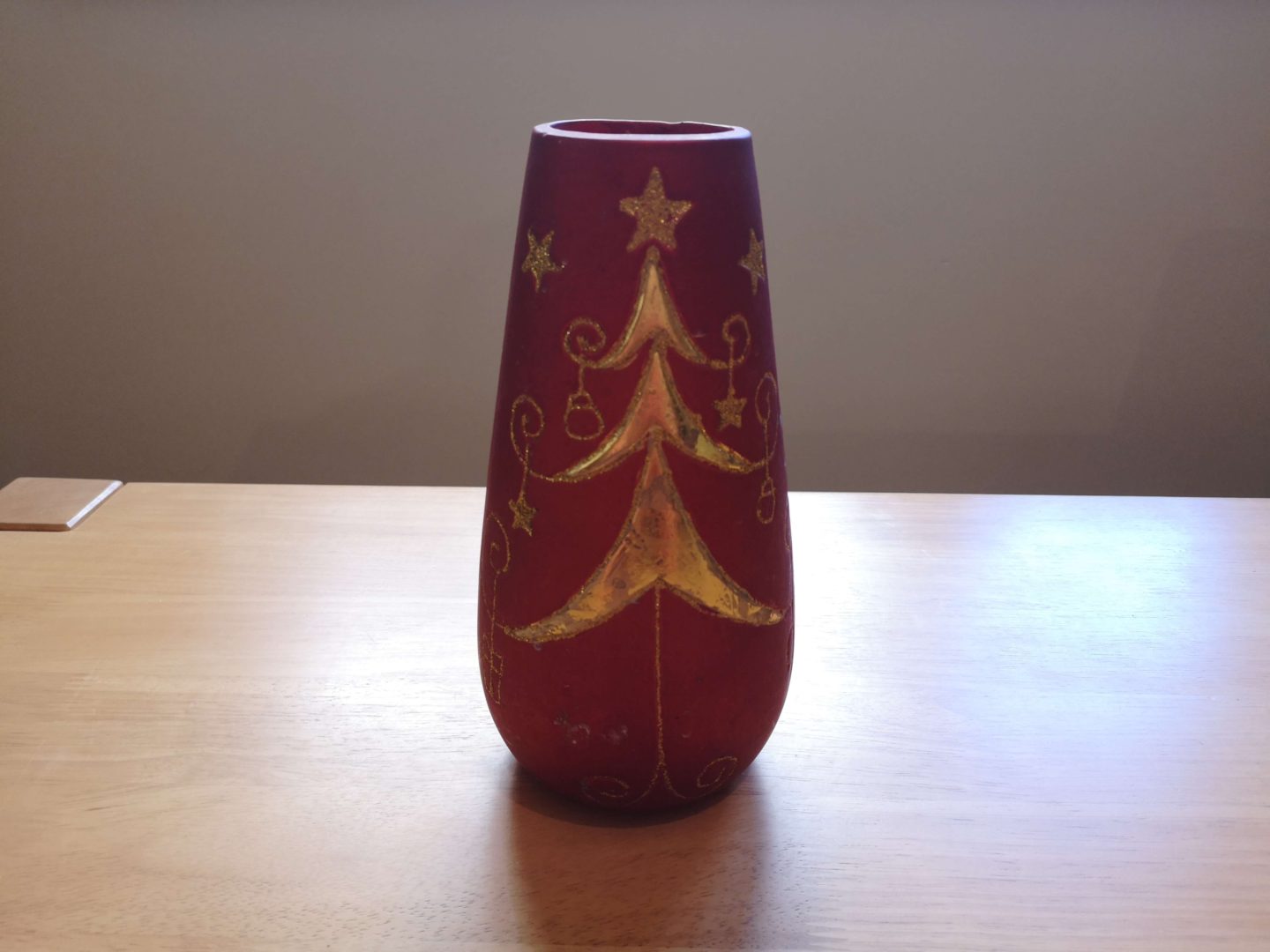 A before picture of a red vase with a gold christmas tree.