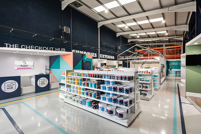 A view of the interior of a paint shop. Many shelves, holding many different coloured paints. 