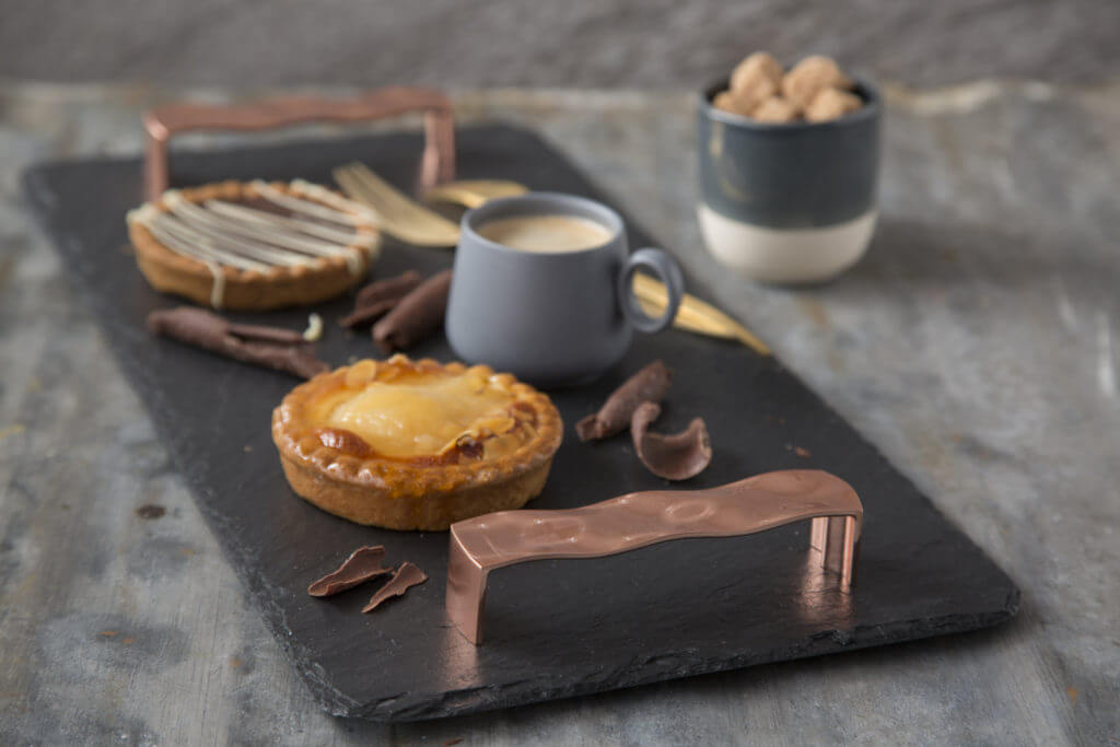 A black slate tea tray with copper handles.