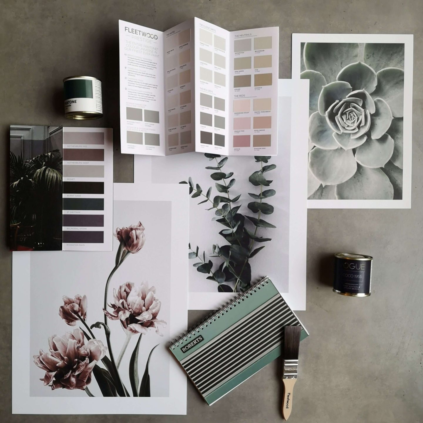 Moodboard using 3 large floral prints, paint colour cards, two paint pots, a paintbrish and a notebook. The colour scheme is green, grey and pink.