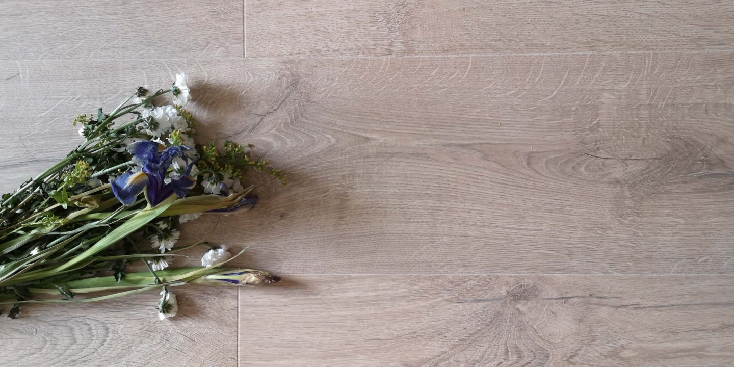 Aerial view of wildflowers lying on beige oak laminate floors.