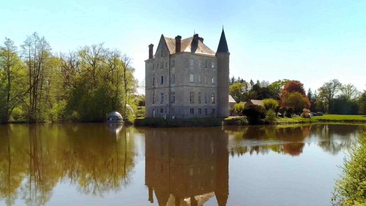 A large castle, with two turrets, surrounded by a moat.