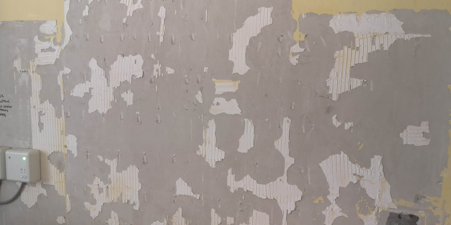A wall with tile removed. Adhesive is still present.