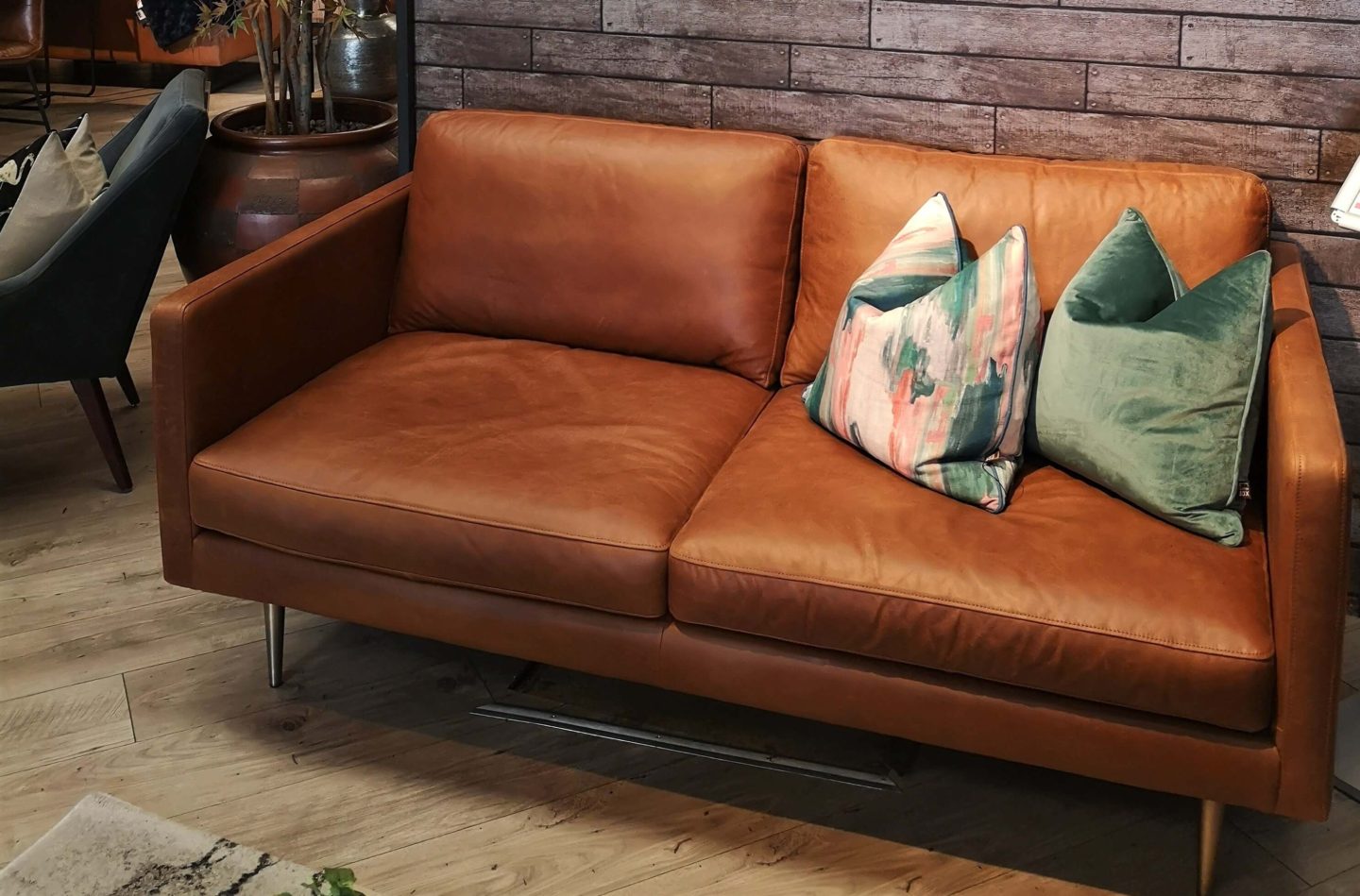 A two seater leather couch with brass legs. 