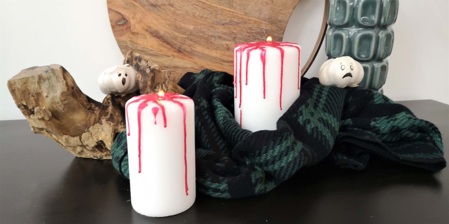 Close up of the white candles with red melted wax dripping down the sides, as if blood.