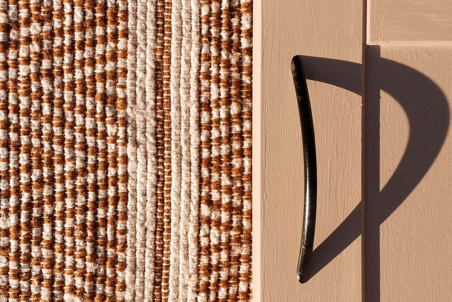 An up close photo of pink cabinet doors with a black handle.