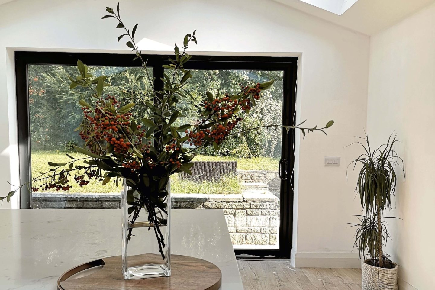 A white kitchen with large sliding doors overlooking a garden.