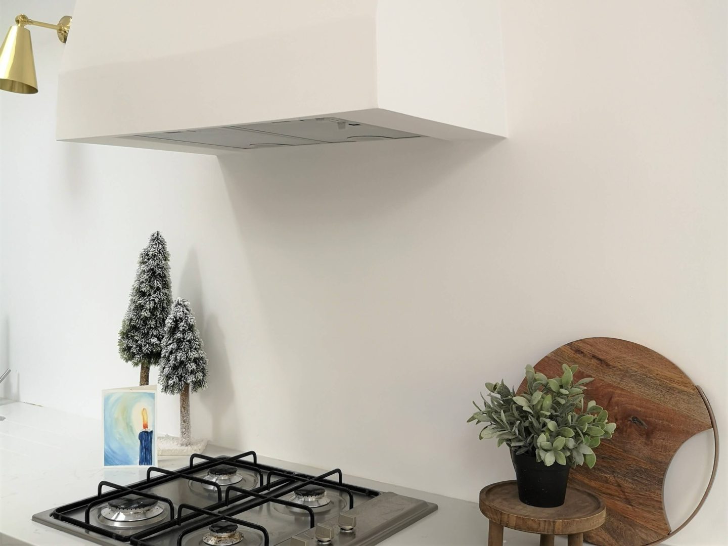 A kitchen gas hob with a built in extractor, plastered and painted the same as the white walls.