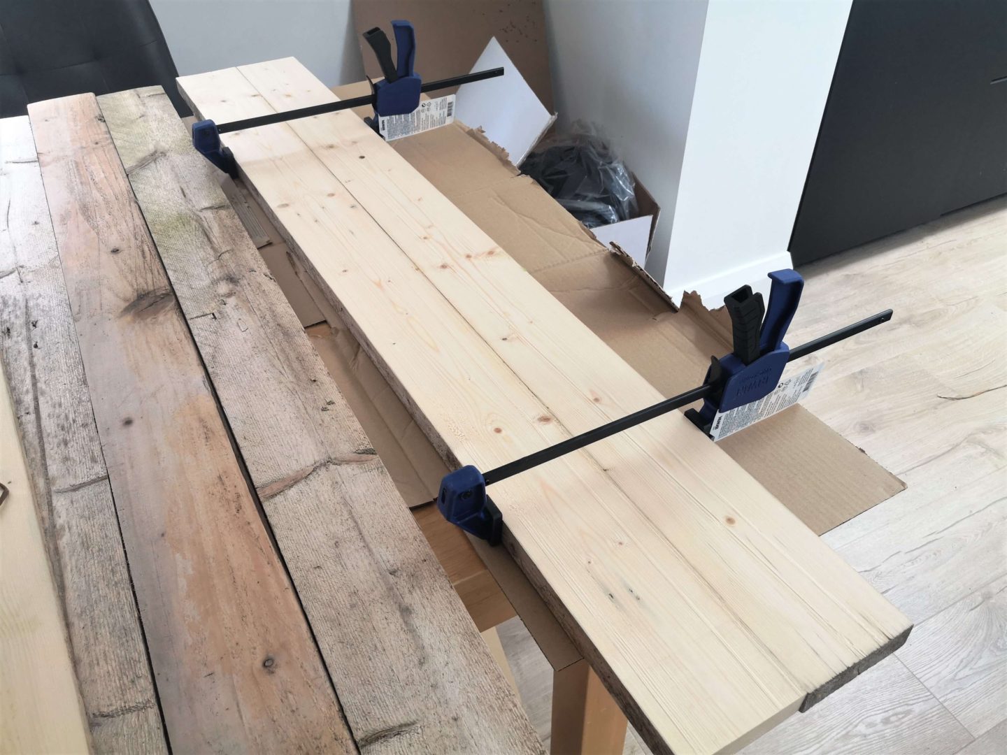 Two wooden boards glued together and clamped.