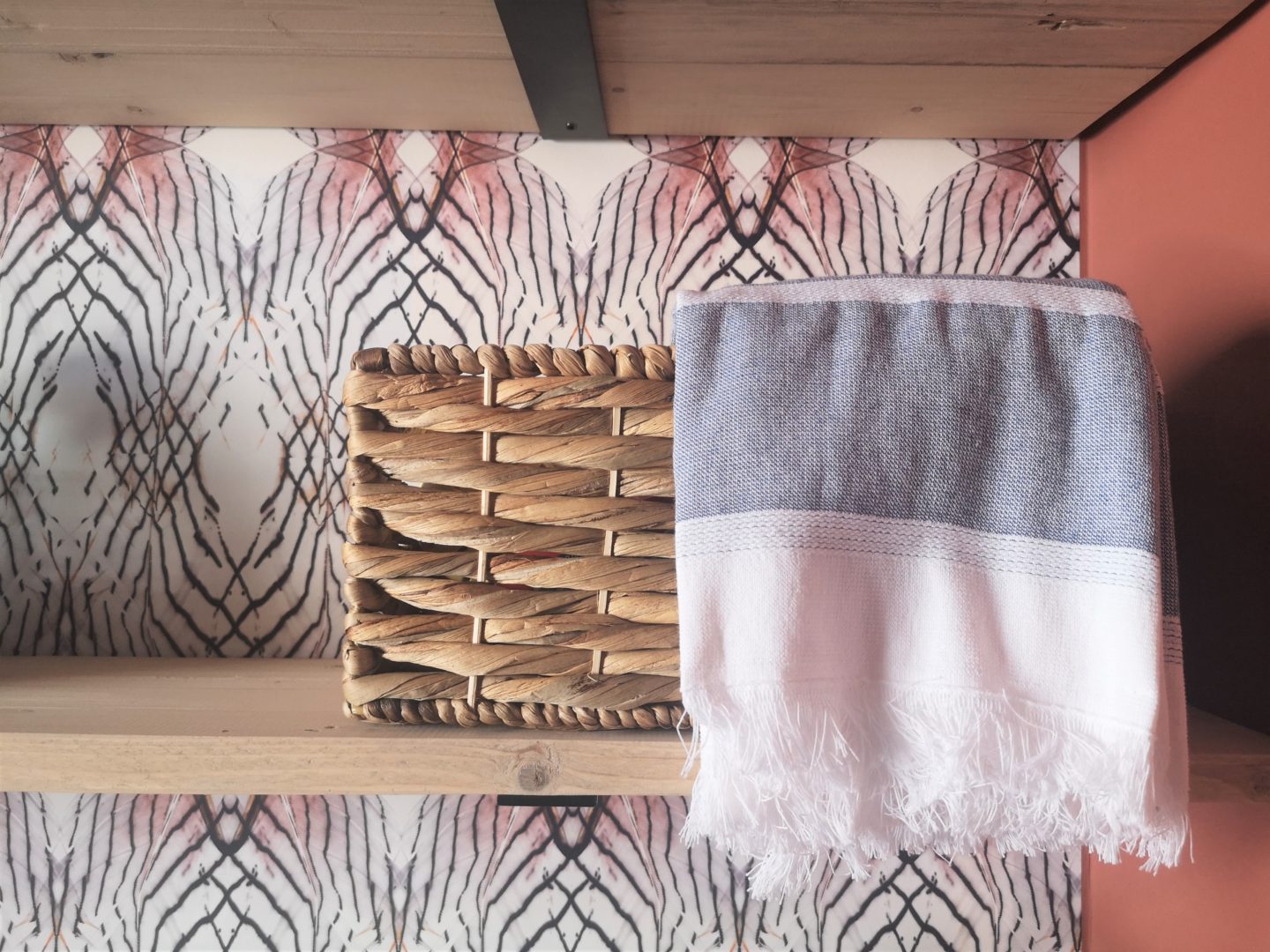 A close up of a basket with a tea towel on a shelf.