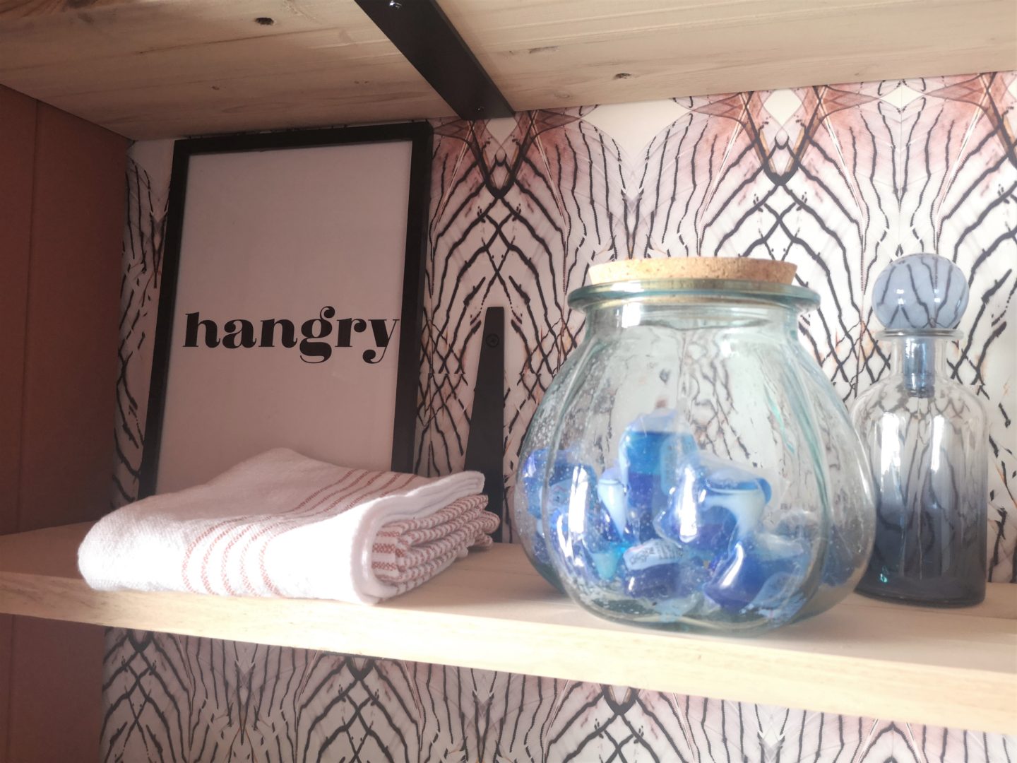 A close up of shelves showing artwork and a glass jar of laundry tabs.