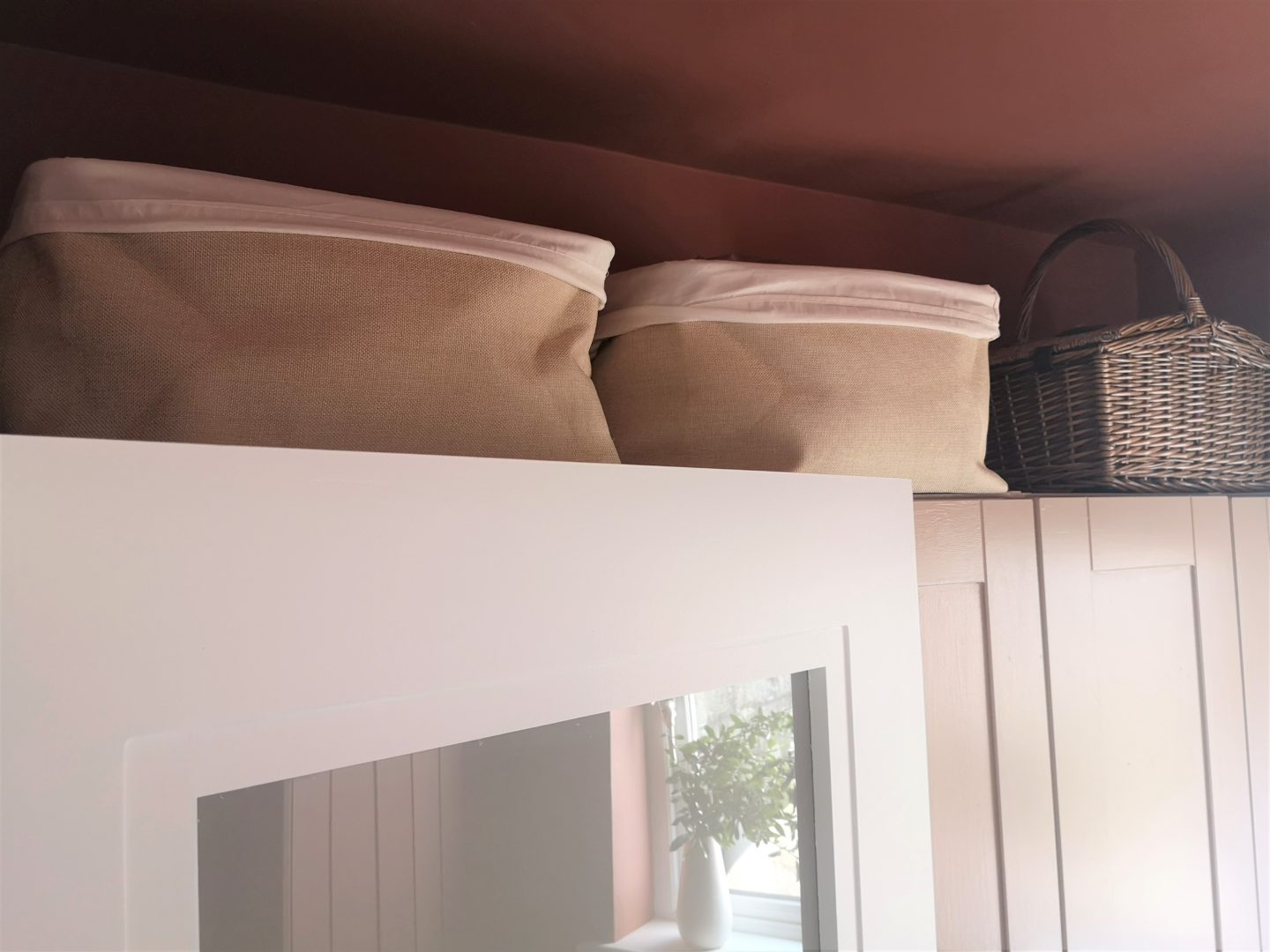 Two baskets above a cupboard. Also shown is the reflection of shelving on a glass door.