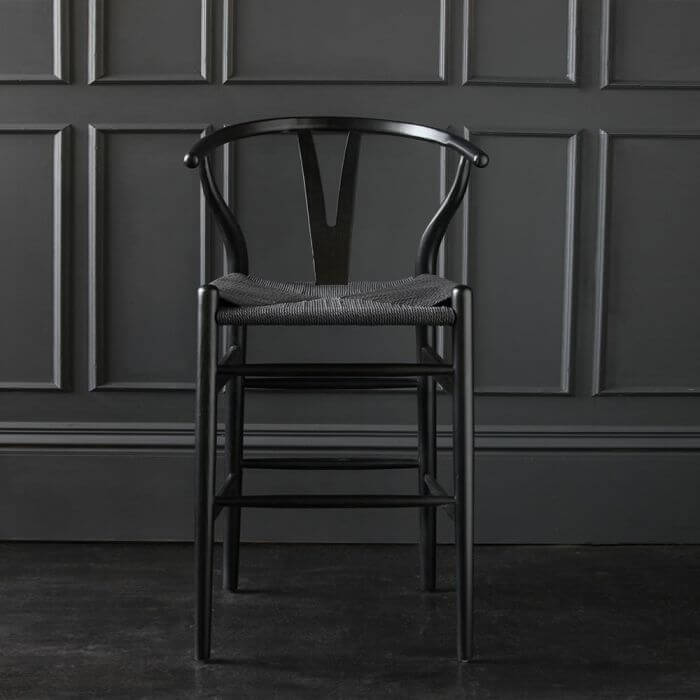 A black wishbone stool with black cord.