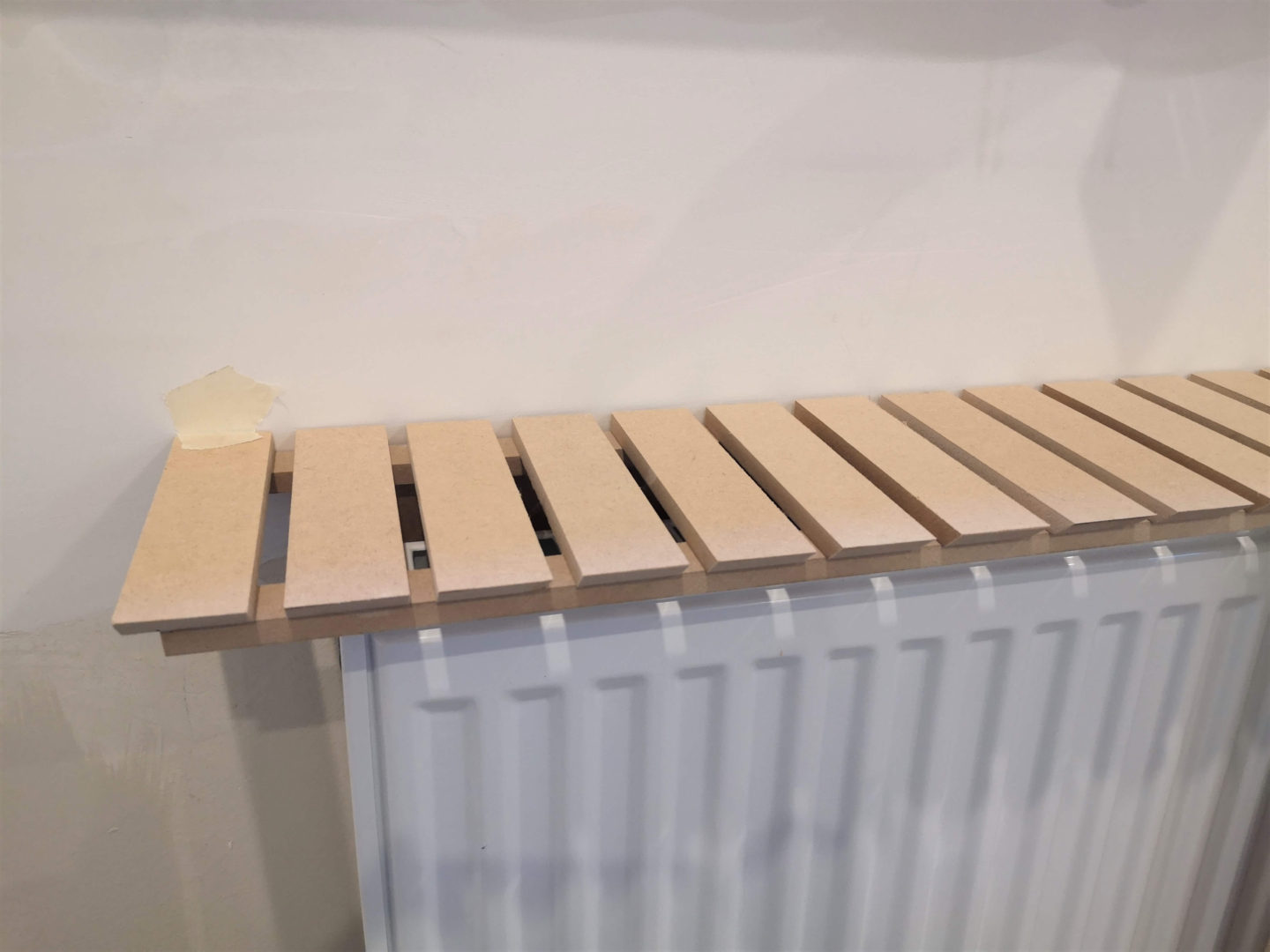Short MDF slats glued together to form the top of a radiator cover.