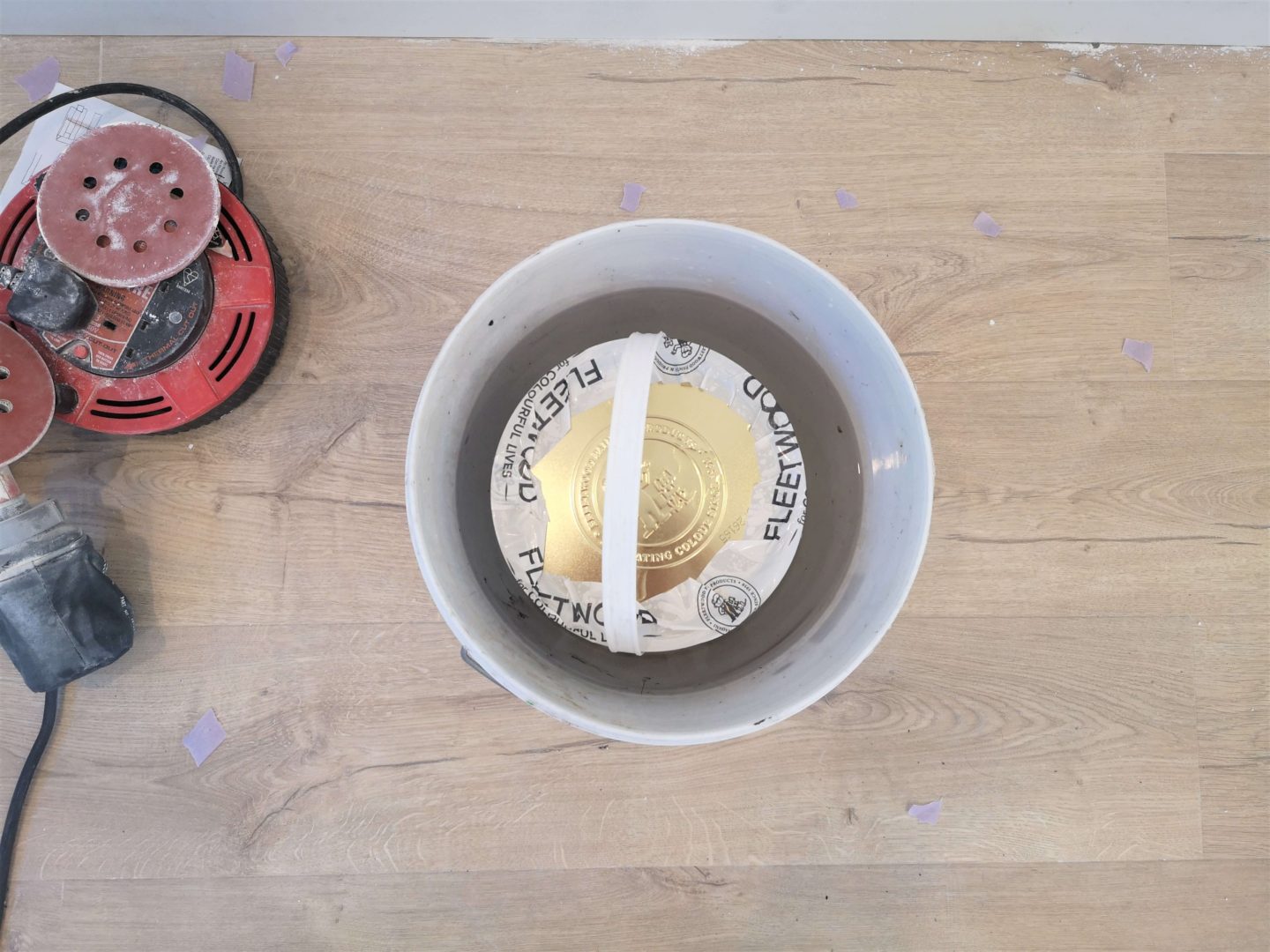 A tin of paint sitting in a bucket of water.