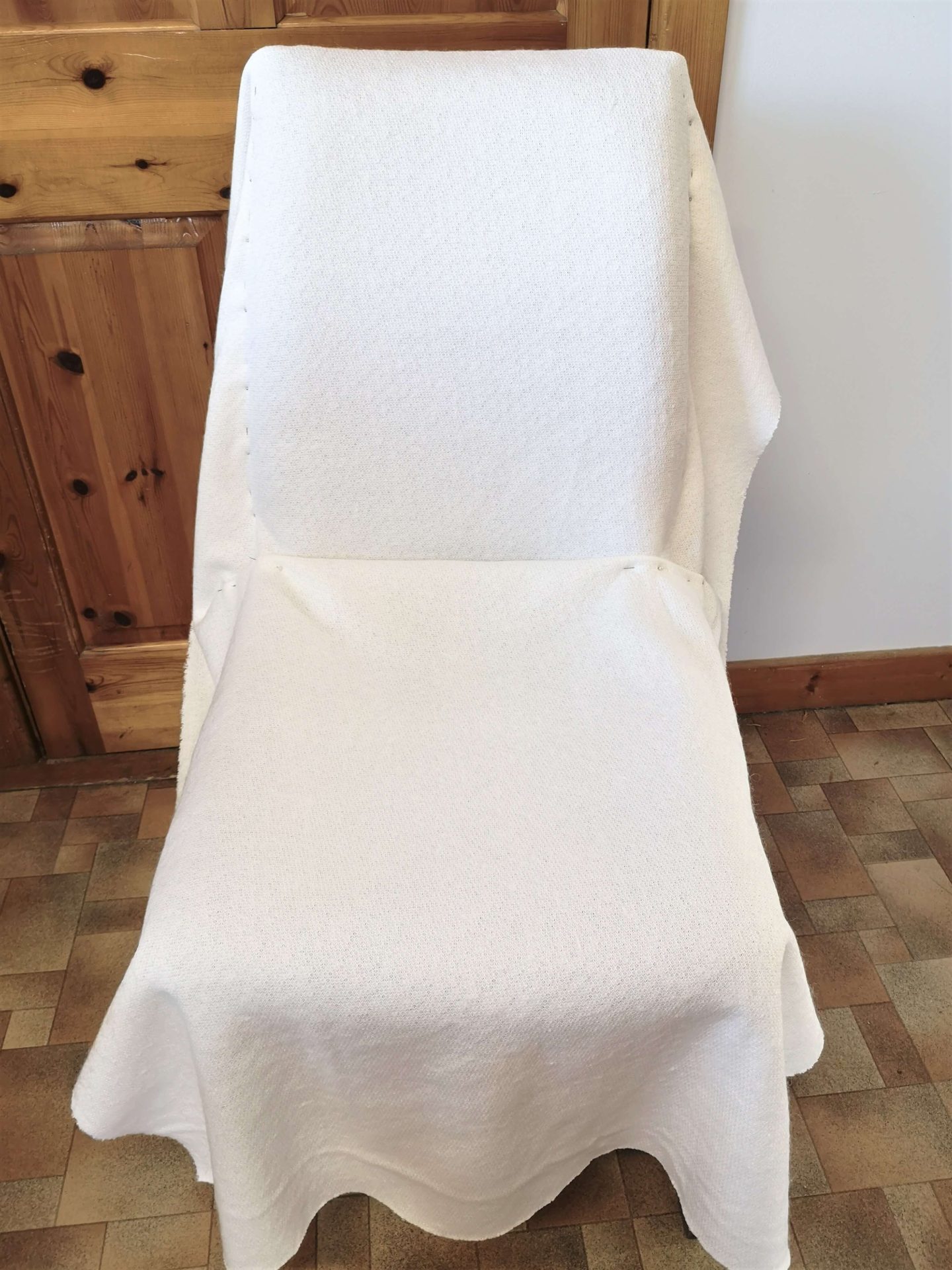 White material draped over a dining chair, held in place with pin needles.