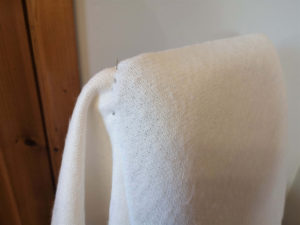 Two pin needles holding the shape of a rounded corner on a dining chair cover.