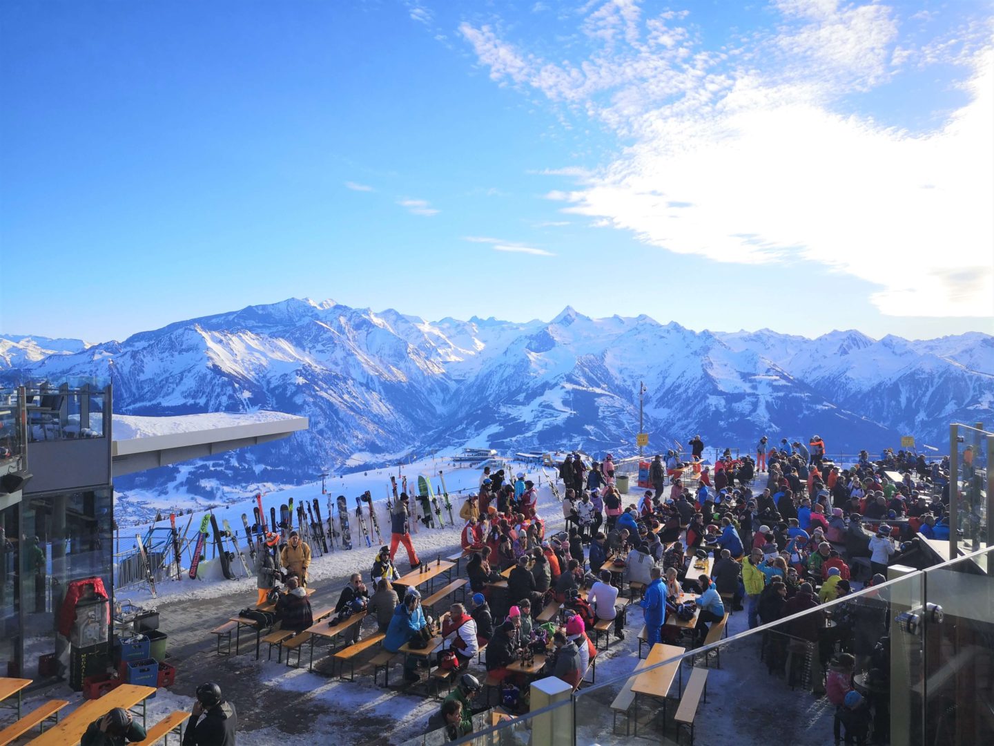 A crowd of people drinking and having fun during apres ski on top of a mountain.