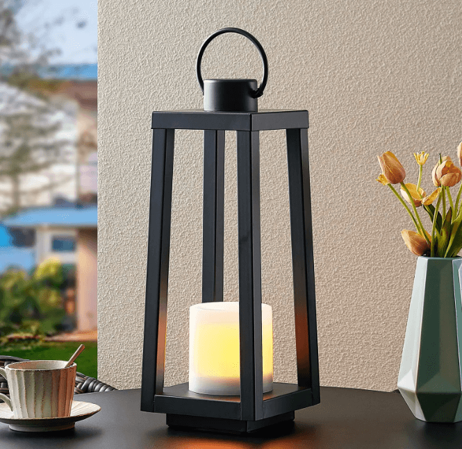 A black lantern with solar powered candle in the middle.