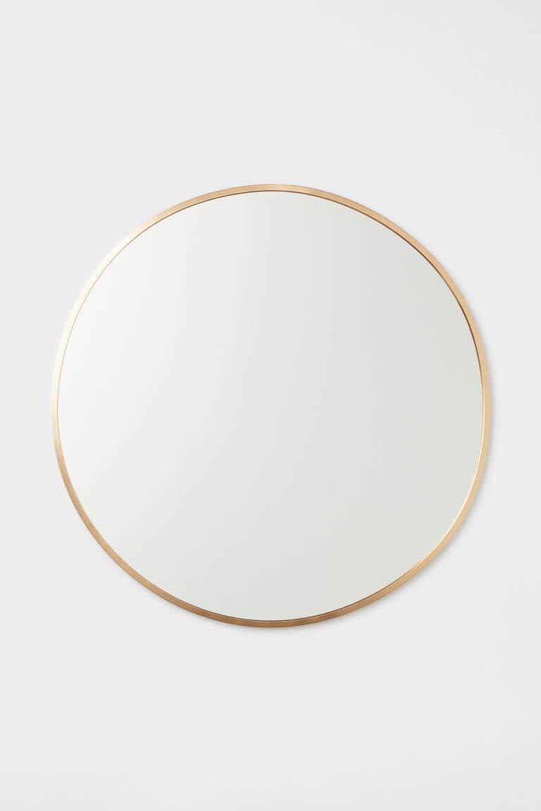 A round mirror with a beige trim.