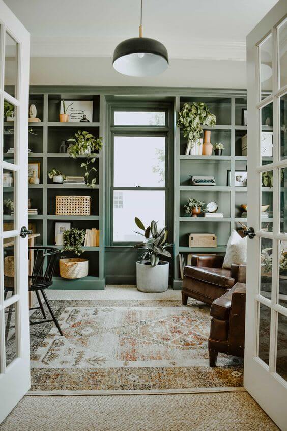 A sitting room with green built-ins, white walls and a vintage living room rug.