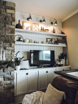 A stone fireplace with shiplap and chunky shelving at the side.