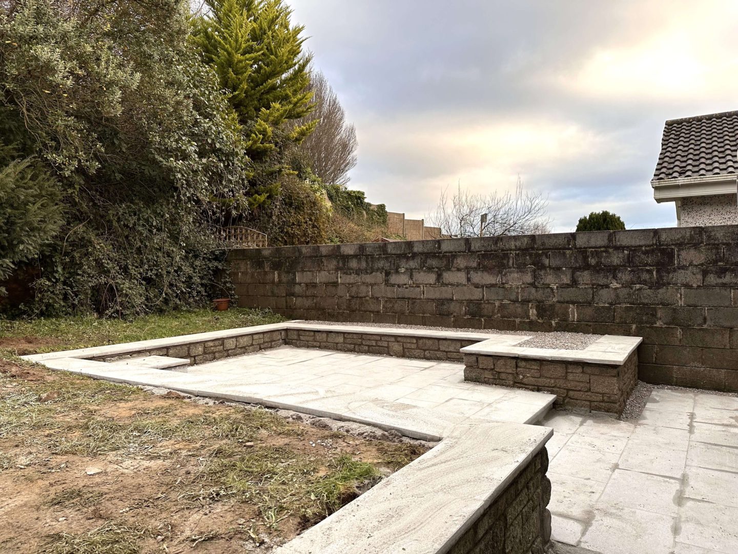 A freshly laid garden patio in a small backyard, using light grey coloured pavers.