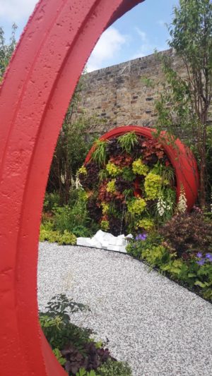 A garden with red sculptures and pea gravel.