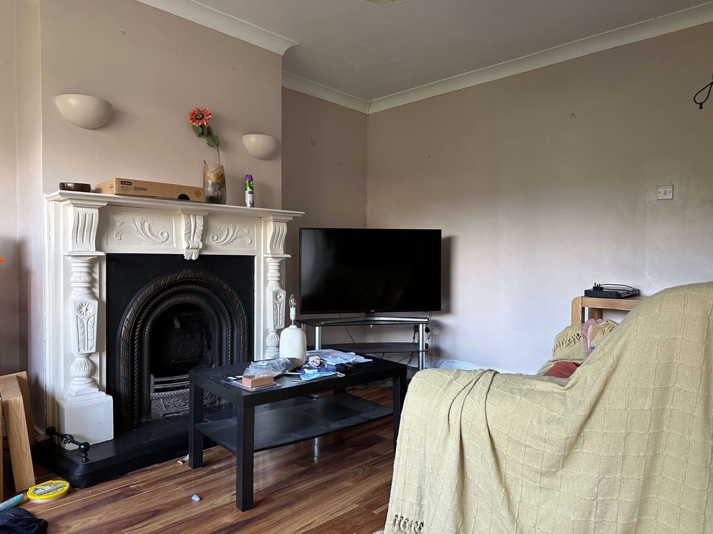 A before picture of a living room with dark taupe walls and a white fireplace.