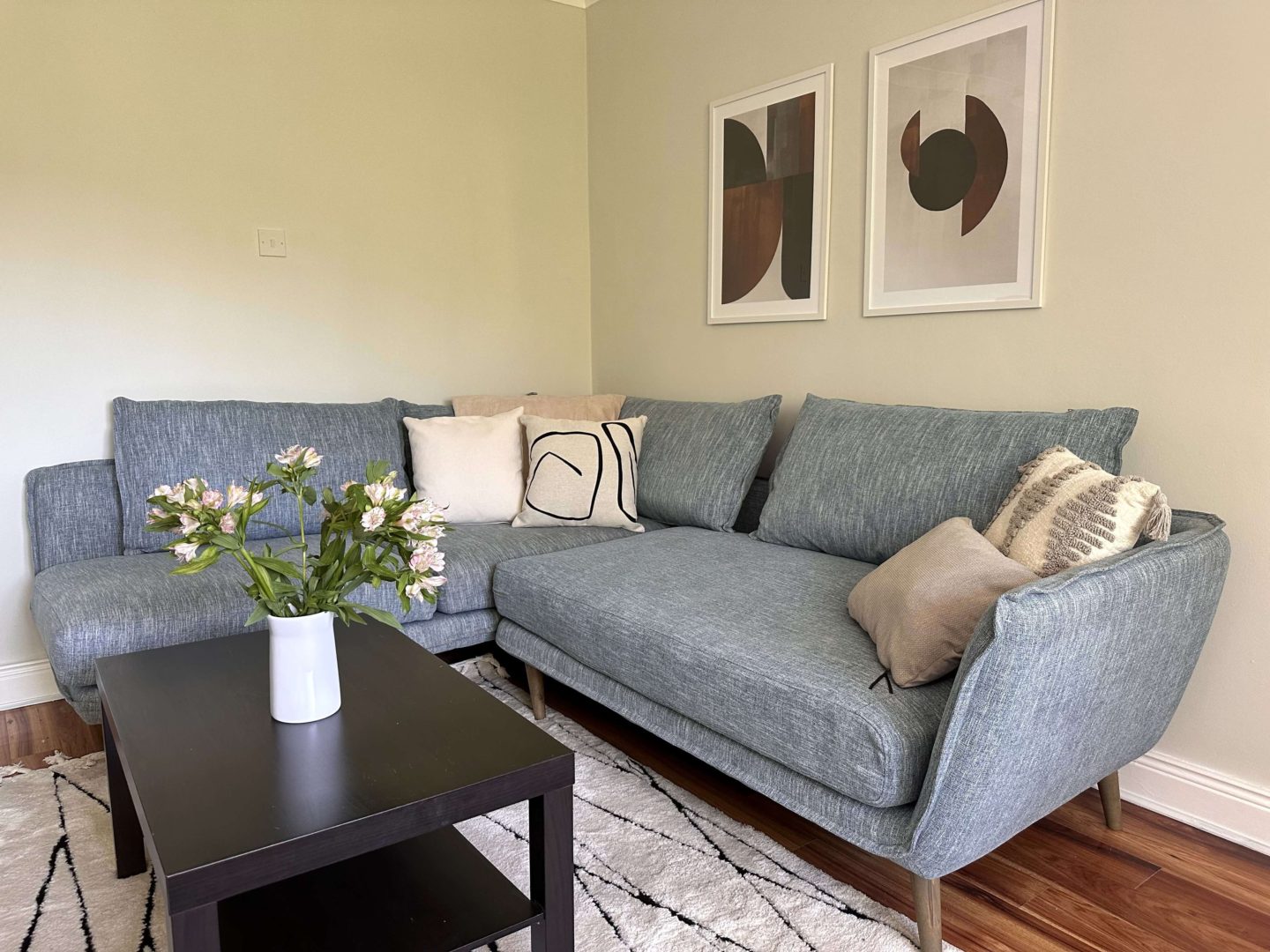 A living room with light green walls and a black and white rug.